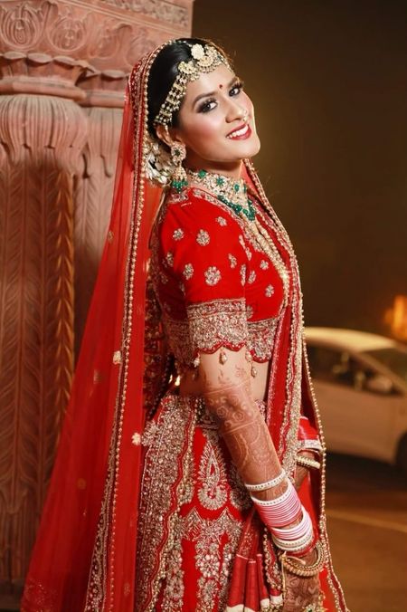A beautiful bride on her wedding in a stunning red bridal lehenga and subtle makeup. 