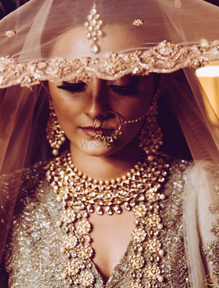 Photo of Pretty bridal portrait in gold lehenga close up shot