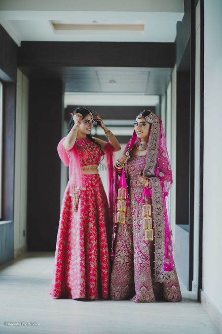 Bride and sister in stunning lehengas in the shades of pink.  