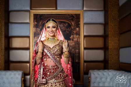 Bride wearing heavy jewellery with her maroon and gold lehenga