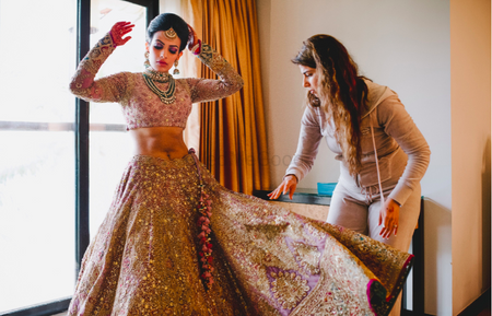 Bride with sister helping set her lehenga skirt