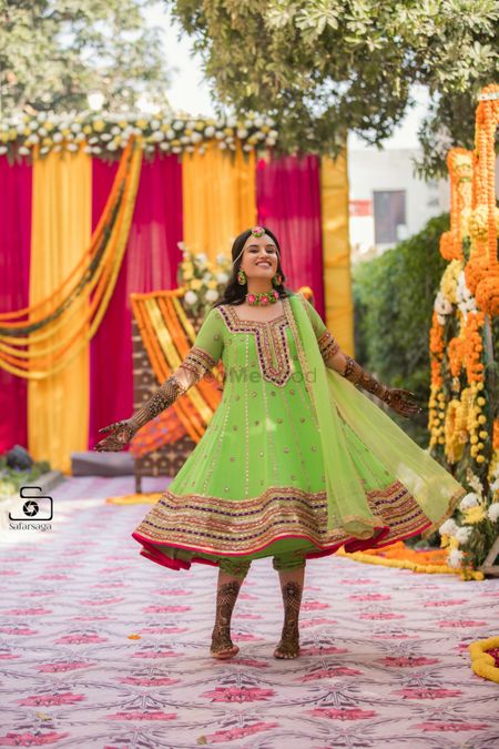 A bride in a green mehndi outfit twirling in happiness
