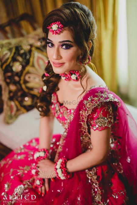 Photo of Bride in red lehenga and floral jewellery with off shoulder