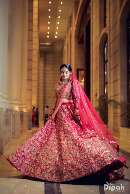 Twirling bride shot in a red and gold lehenga 