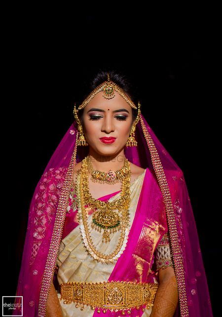 Bride in white and pink wearing south indian temple jewellery