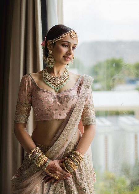 A  bride in a pink lehenga with contrasting green jewellery
