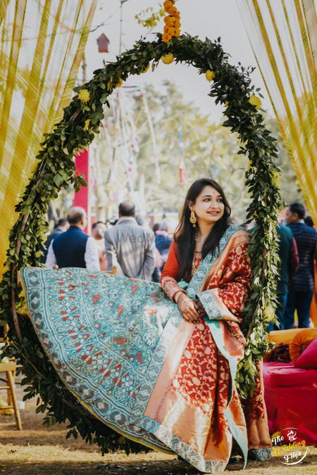 A to be bride sitting in a floral wreath at her mehndi