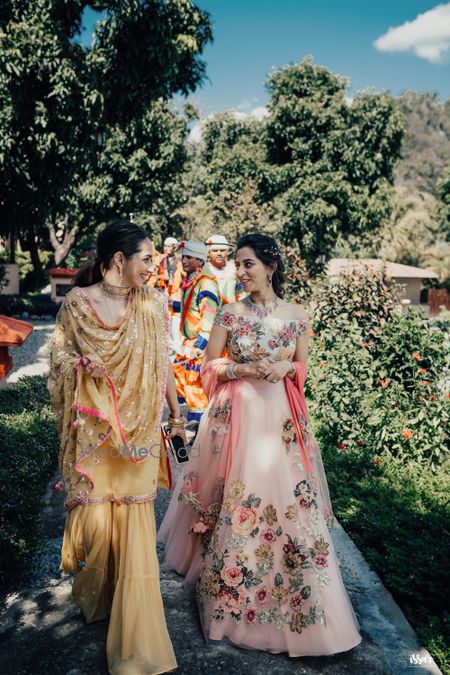 bride in pastel pink lehenga on mehendi with her sister