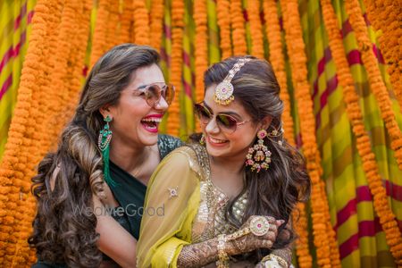 A bride wearing pretty gota jewellery with her sister on her mehndi ceremony 