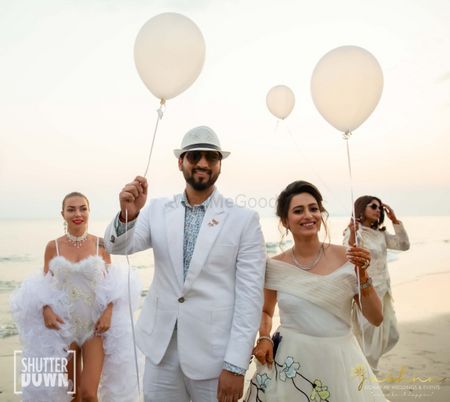 couple entering holding balloons for beach wedding