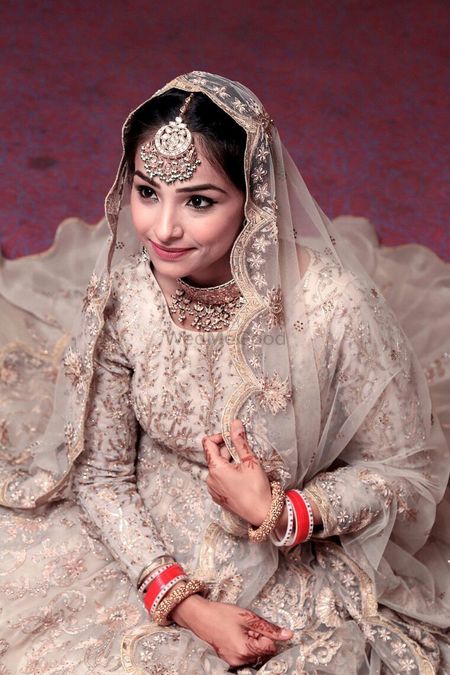 A bride in a silver bridal lehenga and an oversized mangtikka
