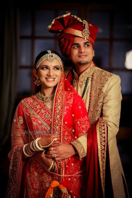 Photo of bright and happy couple shot with the bride in red