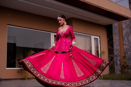 A bride in a red lehenga with peplum top wirling on her wedding day 