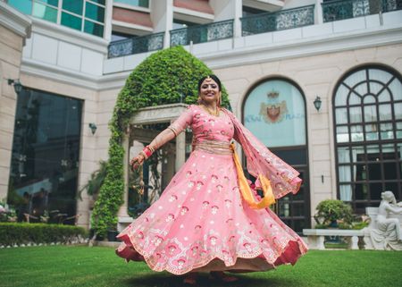 Photo of bride twirling in candy pink lehenga on wedding day