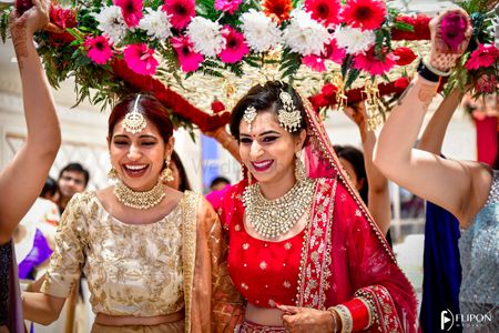 A bride laughs under a phoolon ki chaadar with her sister 