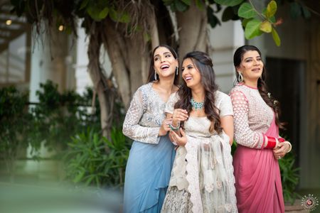 A bride-to-be laughing with her bridesmaids in coordinated pastel outfits 