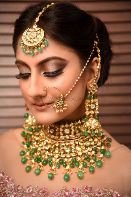 Closeup of a bride wearing a choker and a light nath with green beads
