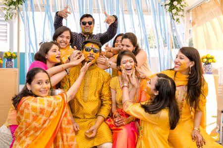 A fun portrait of the bride and groom with friends and family on the haldi. 