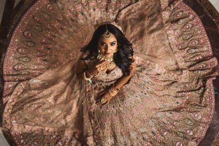 Photo of bride with open hair sitting with flared lehenga