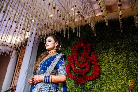 bride in blue lehenga against mehendi ganesh backdrop