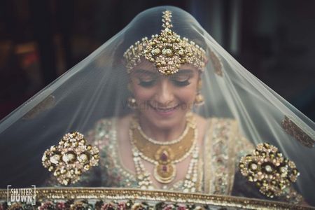 bride holding her sabysachi dupatta as veil shot 