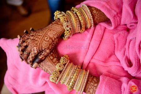 Photo of gold kade and mehendi on bridal hands