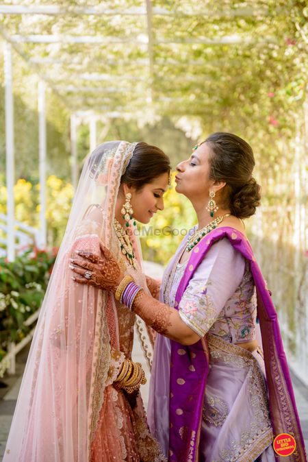 Photo of bride on her wedding day with mom kissing her forehead