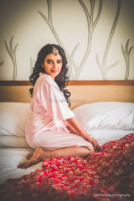 Photo of hotel room bridal portrait with bride in robe on bed