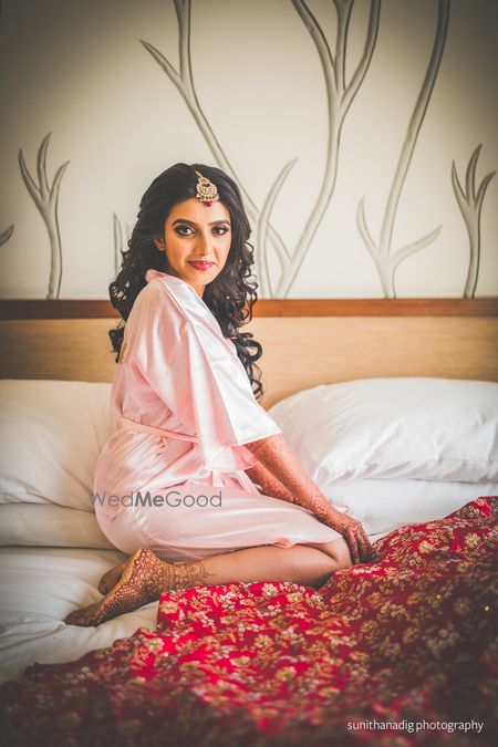 Photo of hotel room bridal portrait with bride in robe on bed