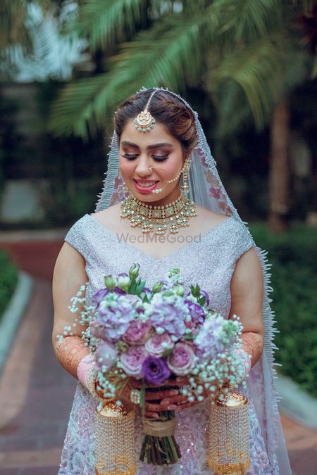 bride holding bouquet wearing lilac lehenga 