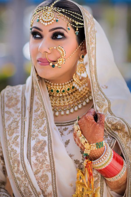 A beautiful bride in white lehenga and gold jewellery. 