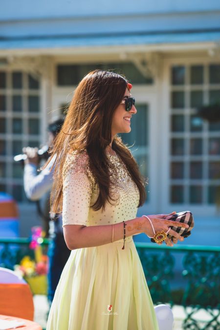 A portrait clicked of the sister of the bride in a yellow outfit and wearing sunglasses 
