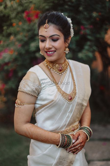 Malayali bride in gold jewellery and white saree. 