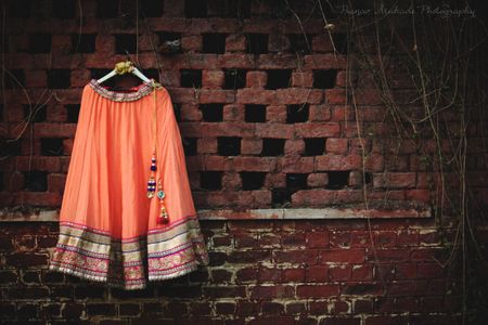 Peach lehenga on hanger in front of rustic wall