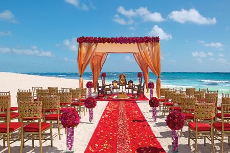 A gorgeous mandap set up by the sea in hues of gold and red 