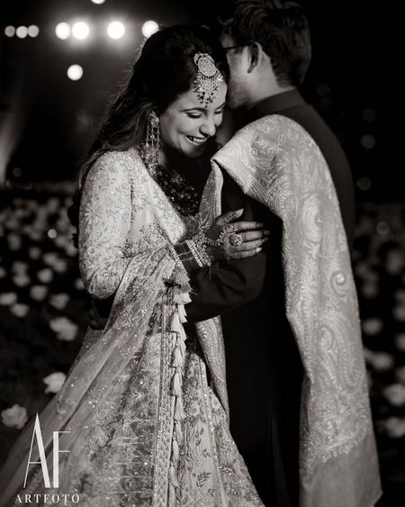 A candid shot of a bride and groom hugging each other.