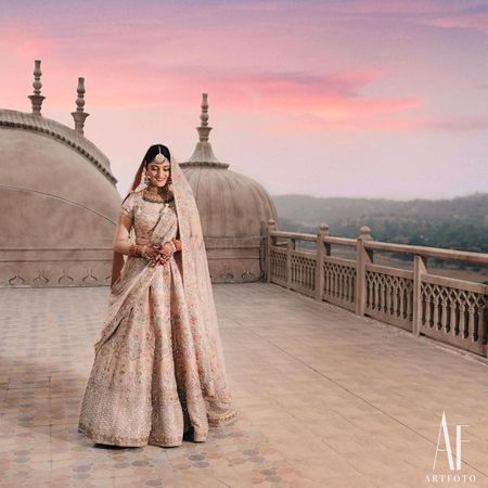A regal shot of a bride dressed in a pink lehenga.
