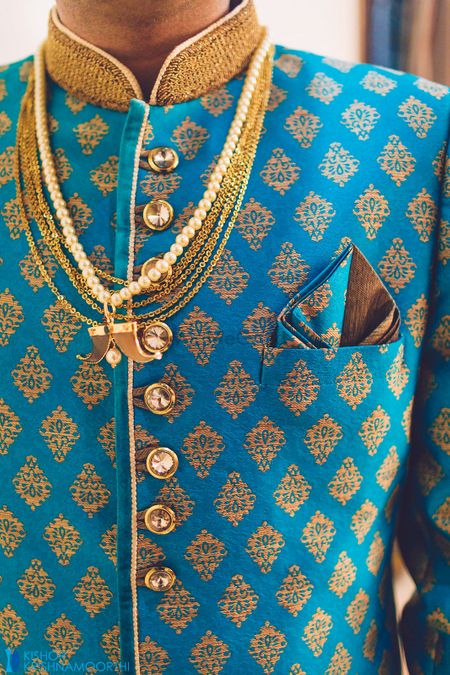 Offbeat blue and gold sherwani with necklace and pocket square