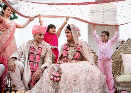 Photo of A cute shot of the couple under a dupatta held by kids