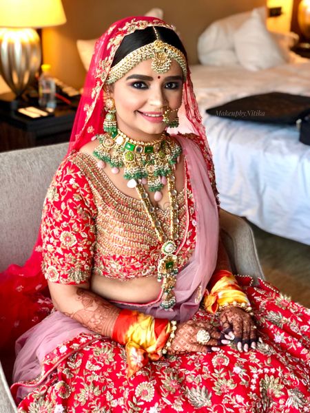 Bride wearing a red lehenga with contrasting jewellery.