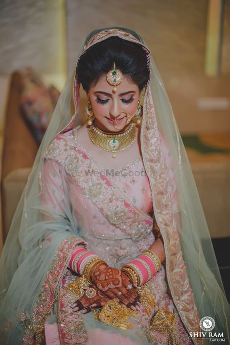 Photo of bride in light pink lehenga with bright chooda
