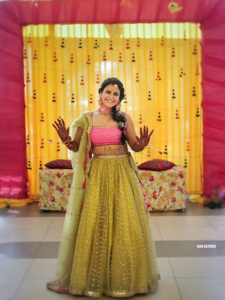 A bride in a light green and pink lehenga for her mehendi