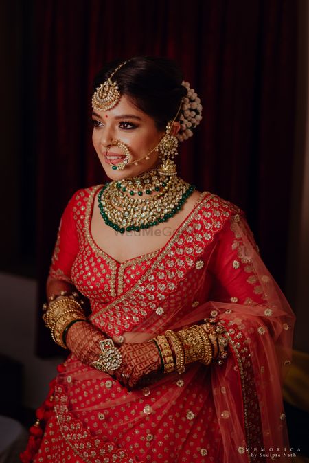 A beautiful bridal portrait of a bride dressed in a red lehenga.