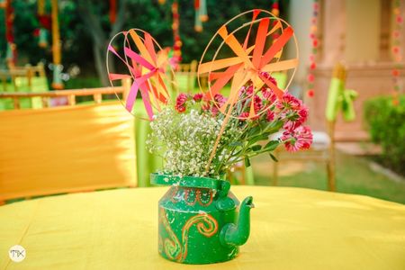 Tea Kettle centrepiece filled with flowers and pinwheels.