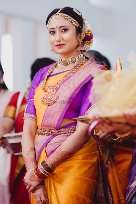 South Indian bride wearing an orange saree with a purple blouse.
