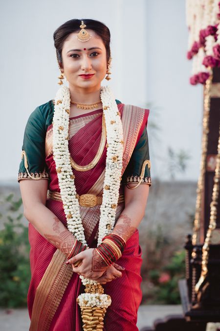 South Indian bride dressed in a maroon saree with a dark green blouse.