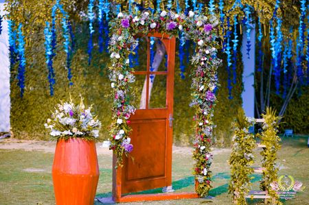 Photobooth with a wooden door frame and a drum decorated with flowers.
