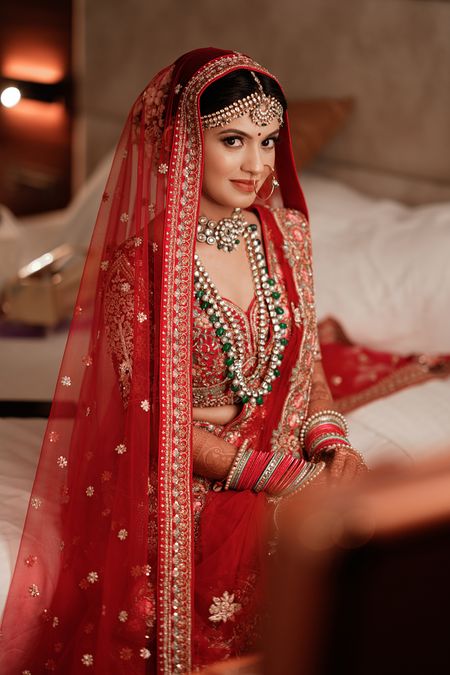 Photo of Bride in red lehenga posing on her wedding day.