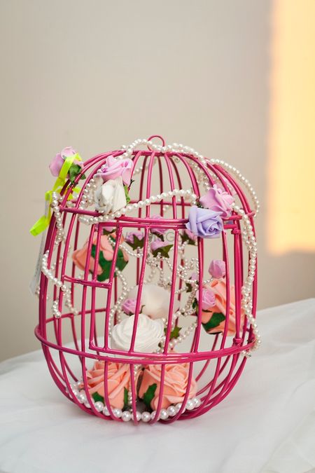 Photo of birdcage packaging with flowers and sweet treats