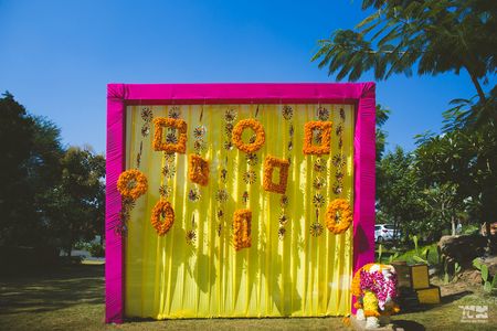 Photo of Mehendi Photo Booth idea with yellow backdrop and genda pool frames